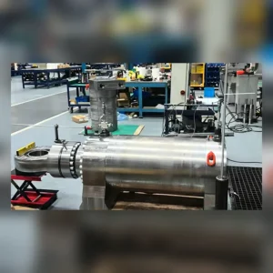 Large cylindrical hydraulic machine part on factory floor.