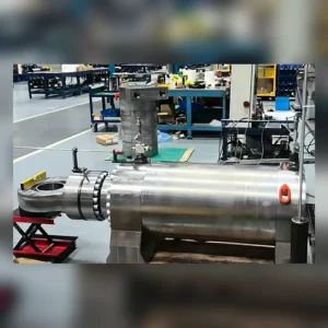 Large cylindrical hydraulic machine part on factory floor.