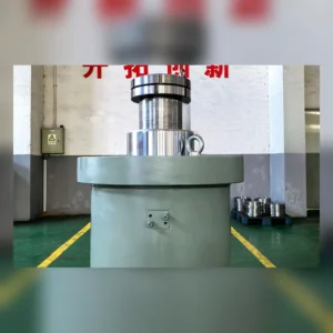 Industrial cylinder with rod on factory floor; visible mounting fixtures.