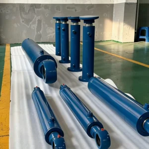 Blue industrial cylinders on factory floor with visible mounting points.
