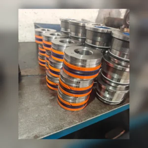Stacked cylindrical components with orange bands on factory floor.