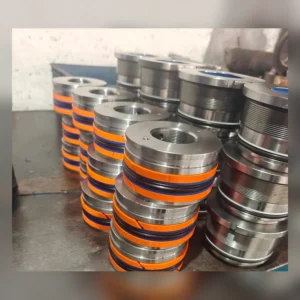 Stacked cylindrical components with orange bands on factory floor.